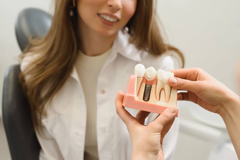 Dental Patient Getting Shown A Dental Implant Model During Her Consultation in Woodbury, MN
